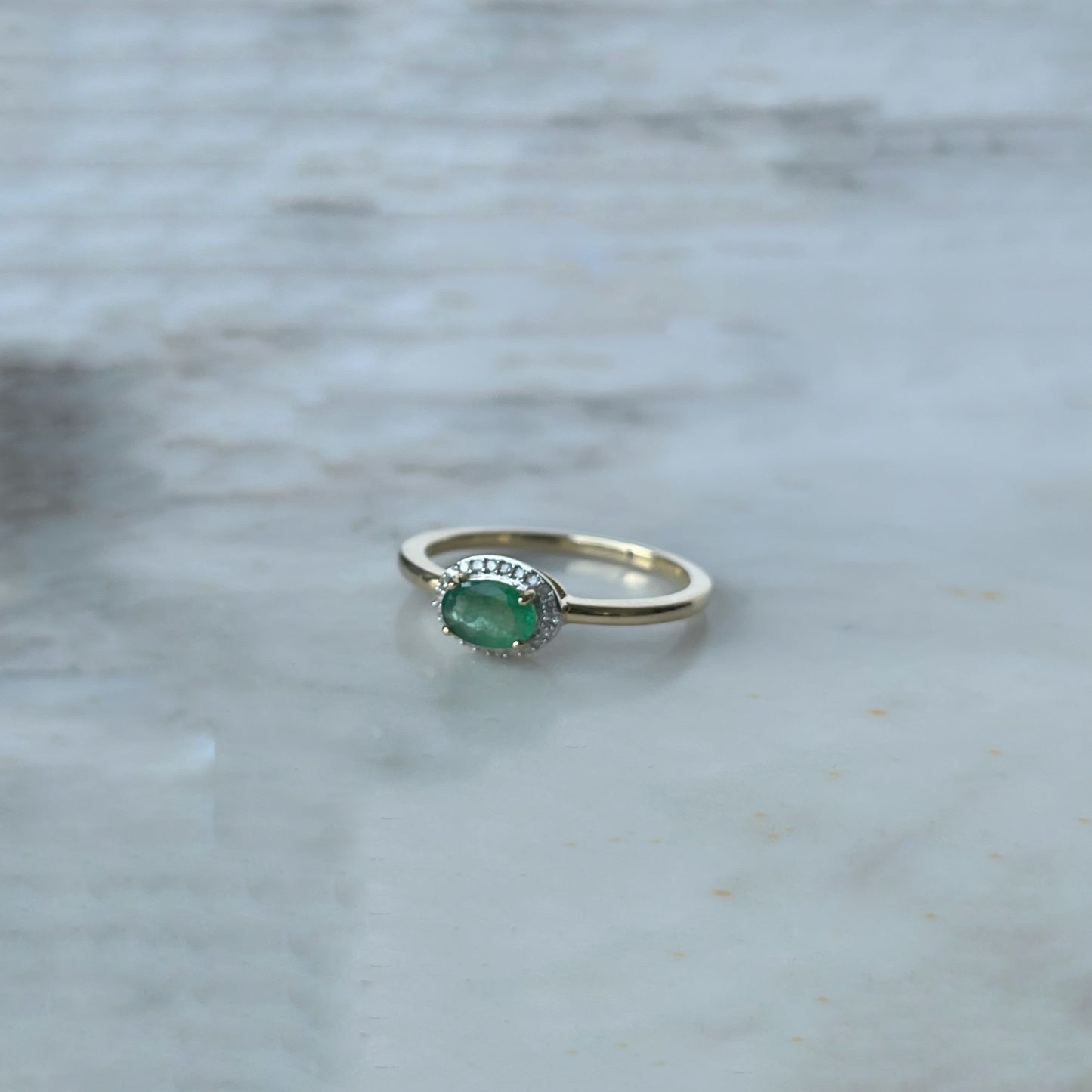 Anillo en oro amarillo 14k con esmeralda ovalada y halo de diamantes 0.10ctw