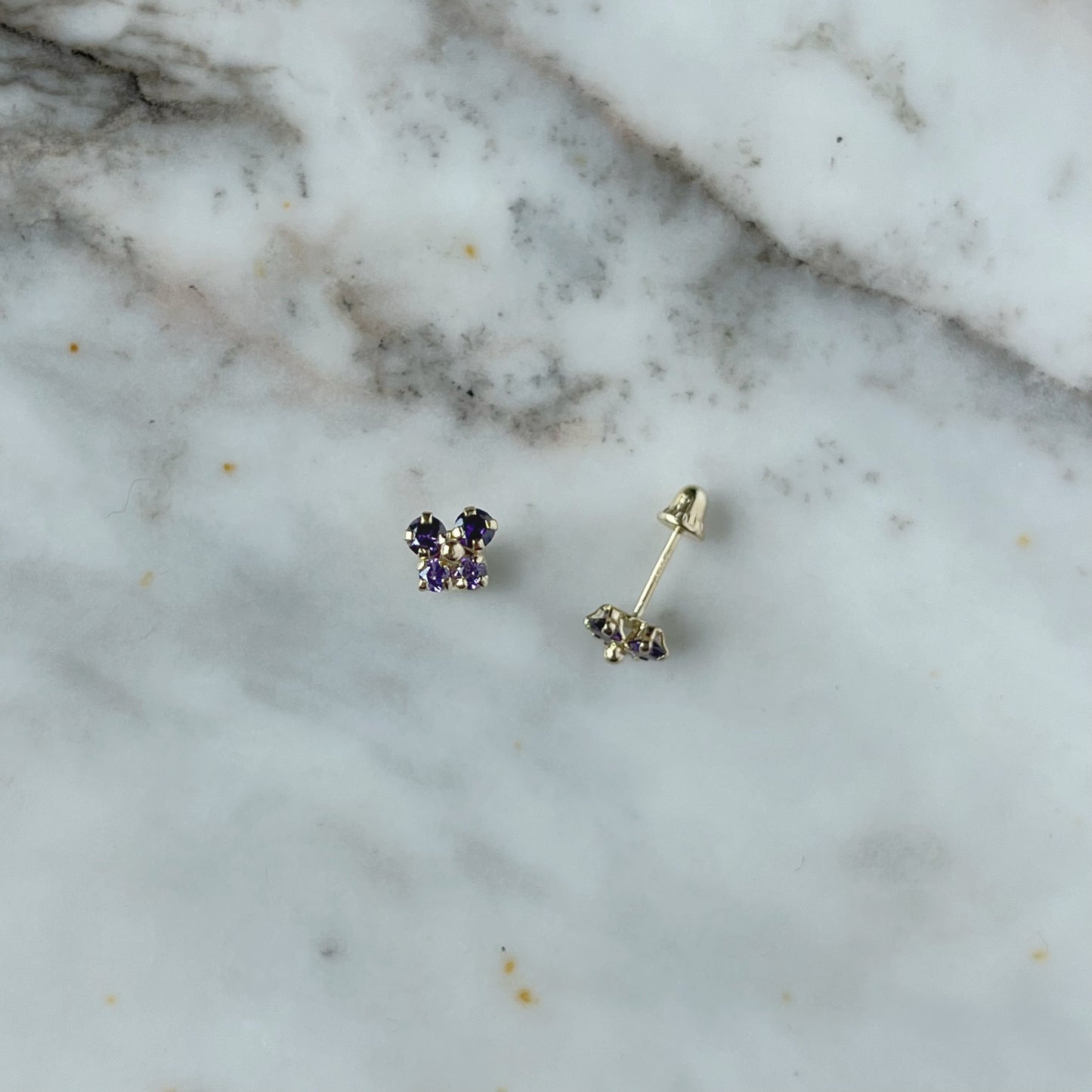 Aretes en oro amarillo 14k con mariposita de circonitas moradas con broche rosca