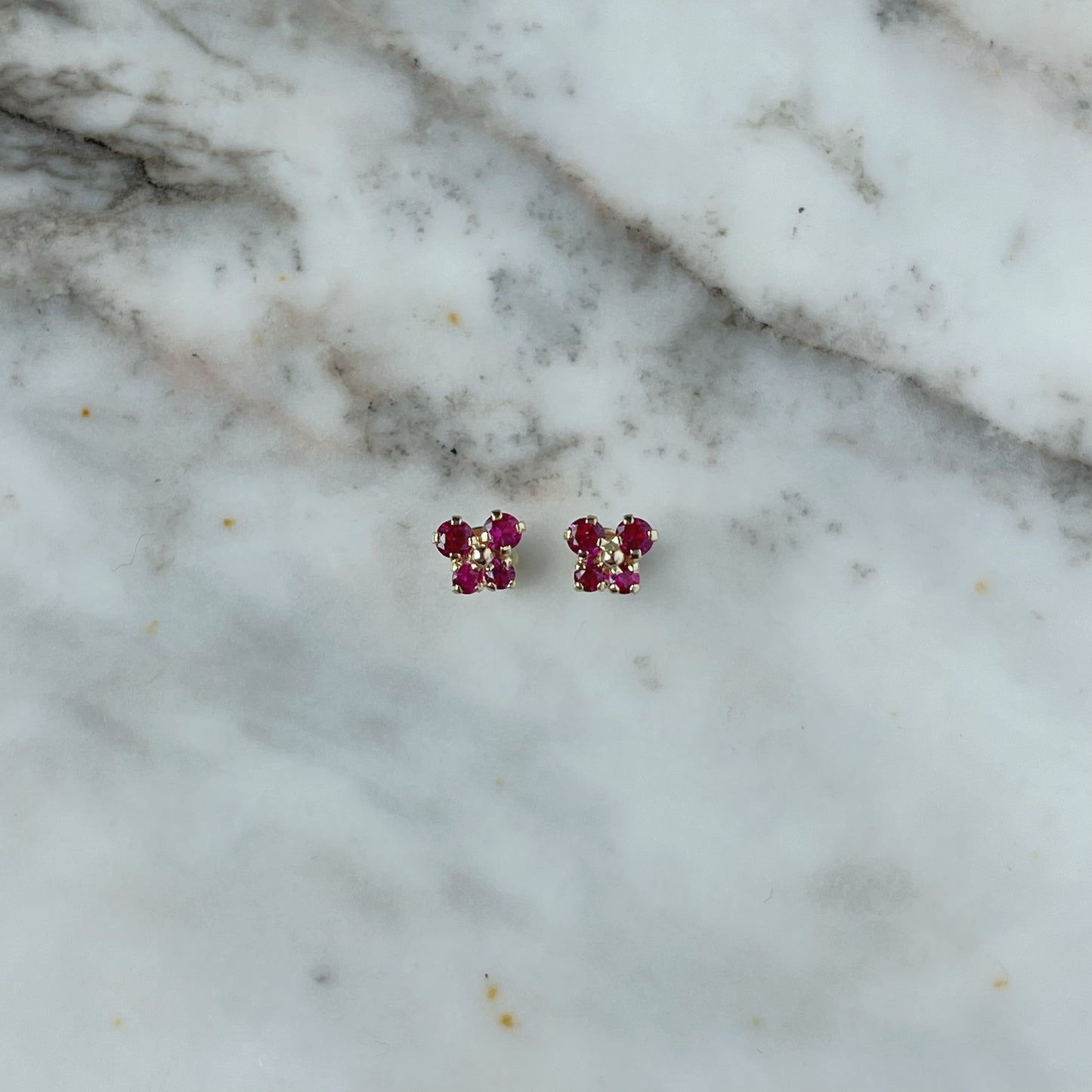 Aretes en oro amarillo 14k con mariposita de circonitas rojas con broche rosca