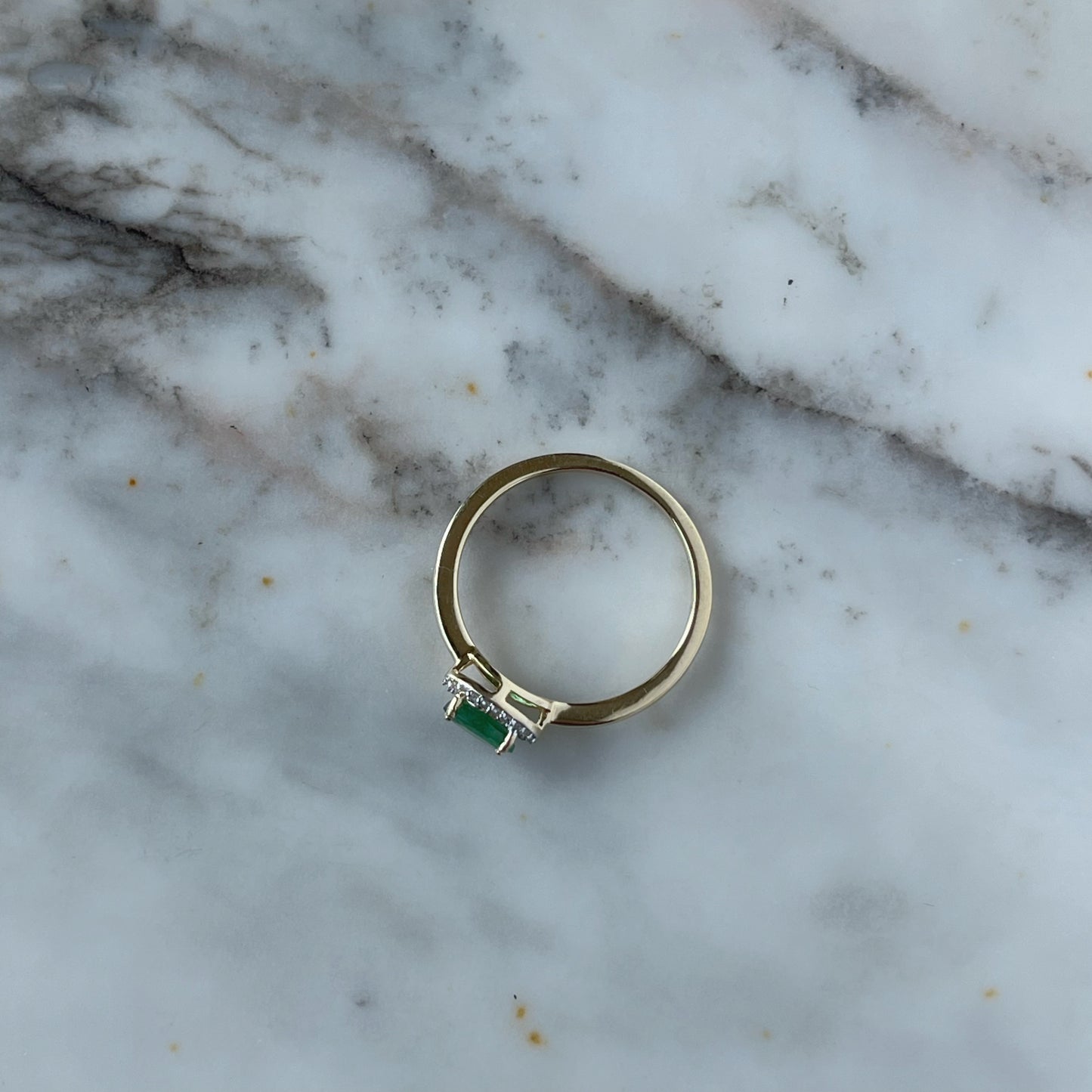 Anillo en oro amarillo 14k con esmeralda ovalada y halo de diamantes 0.10ctw