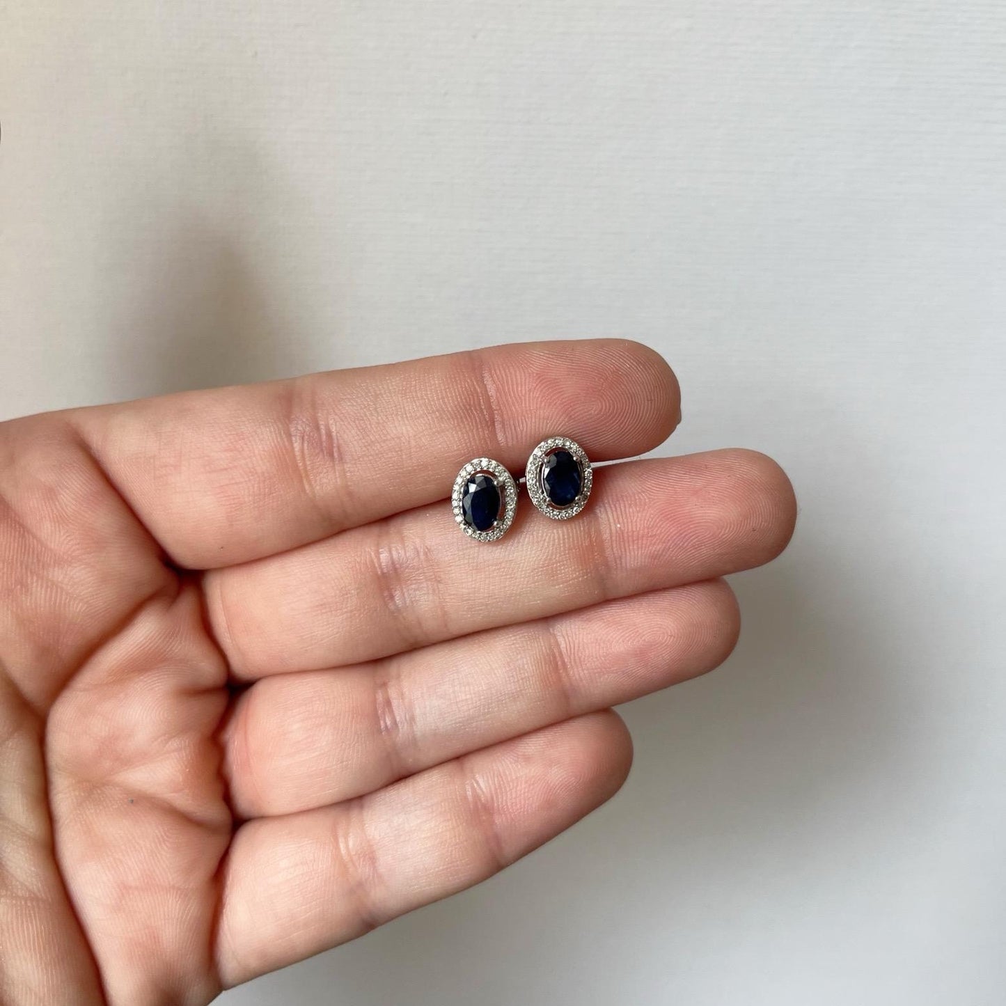 Aretes en oro blanco 10k con zafiro ovalado y halo de diamantes 0.15ctw