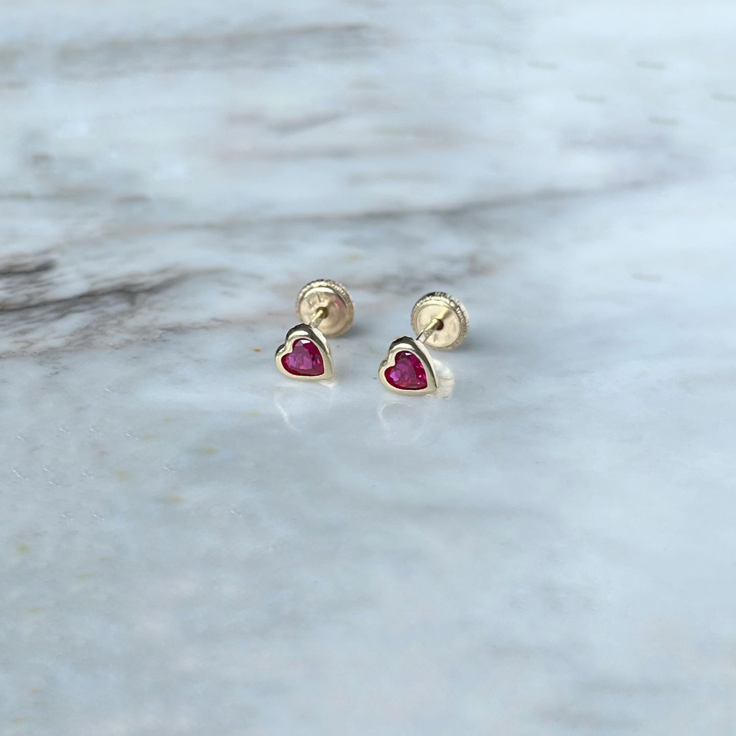 Aretes en oro amarillo 14k circonita roja de corazón con bisel con broche rosca