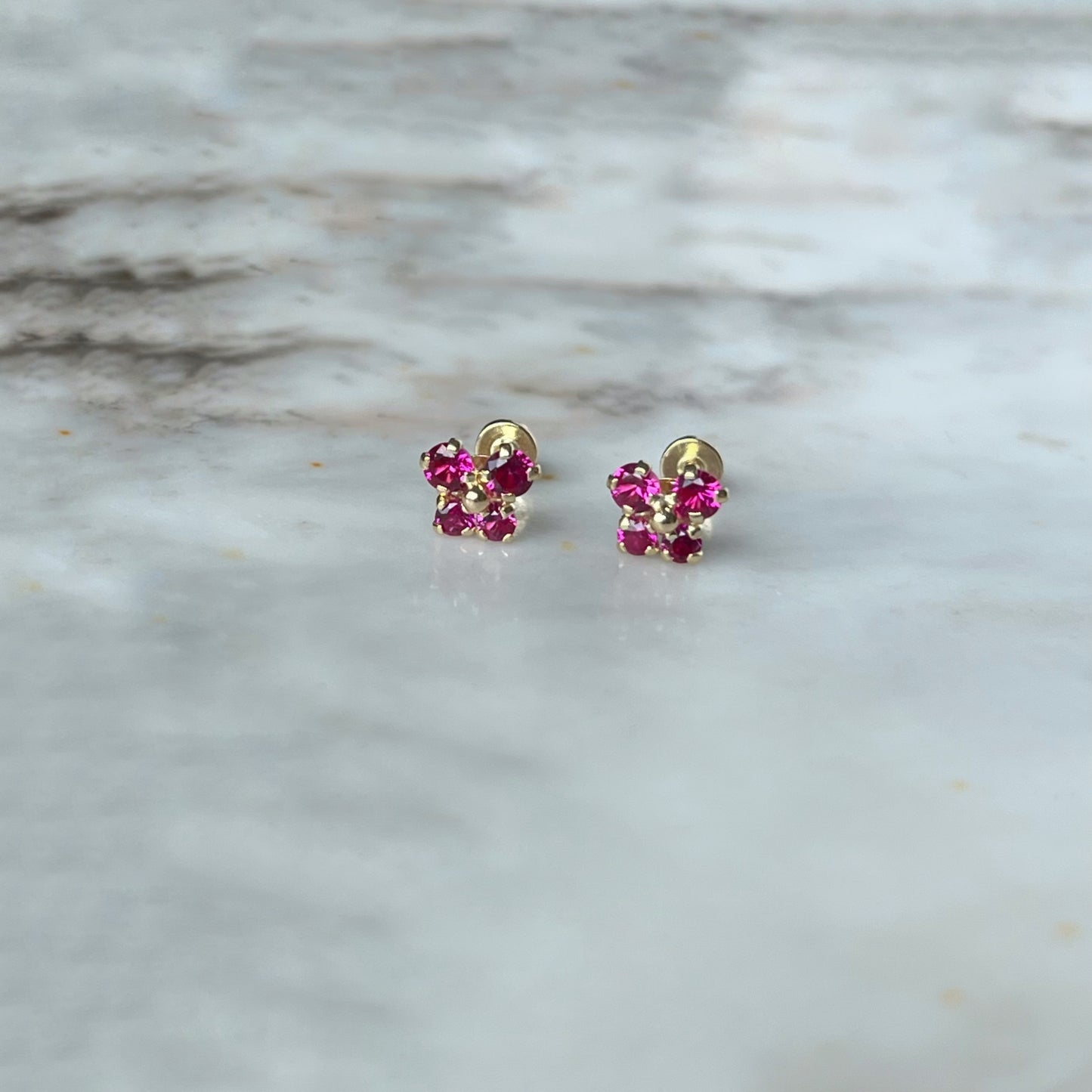 Aretes en oro amarillo 14k con mariposita de circonitas rojas con broche rosca