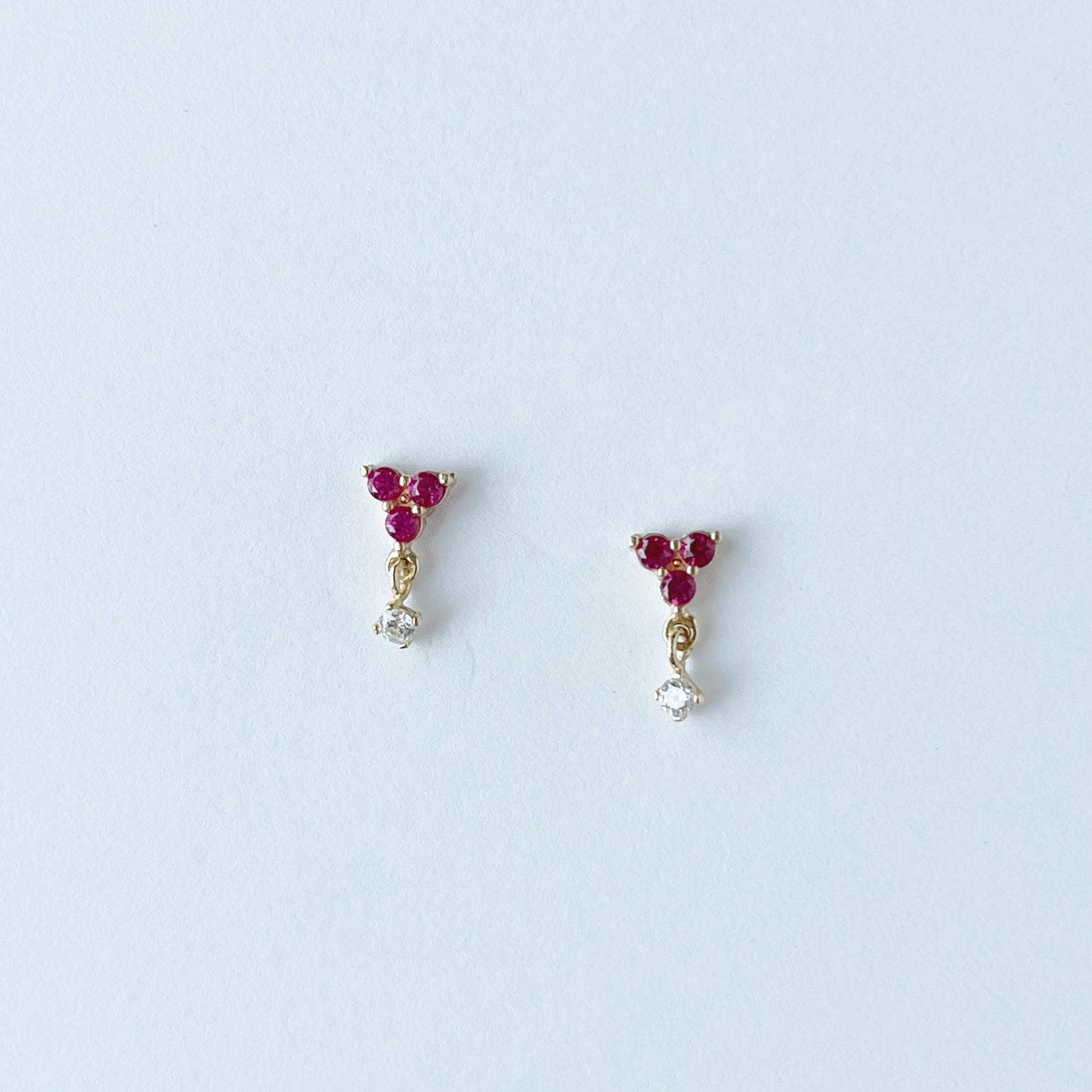 Arete con tres circonitas fucsia y una circonita colgante en oro amarillo de 14K con tope rosca