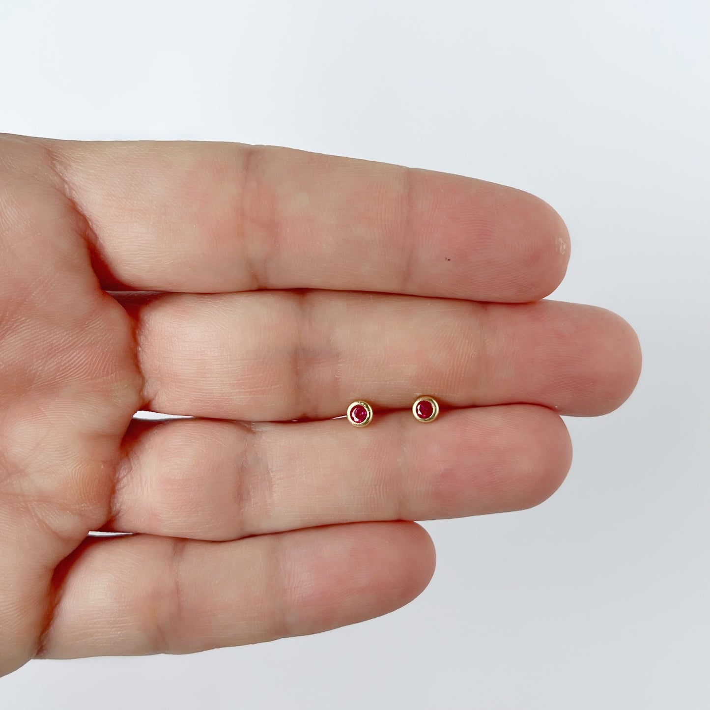 Aretes en oro amarillo 14k con circón biselado rojo con broche rosca