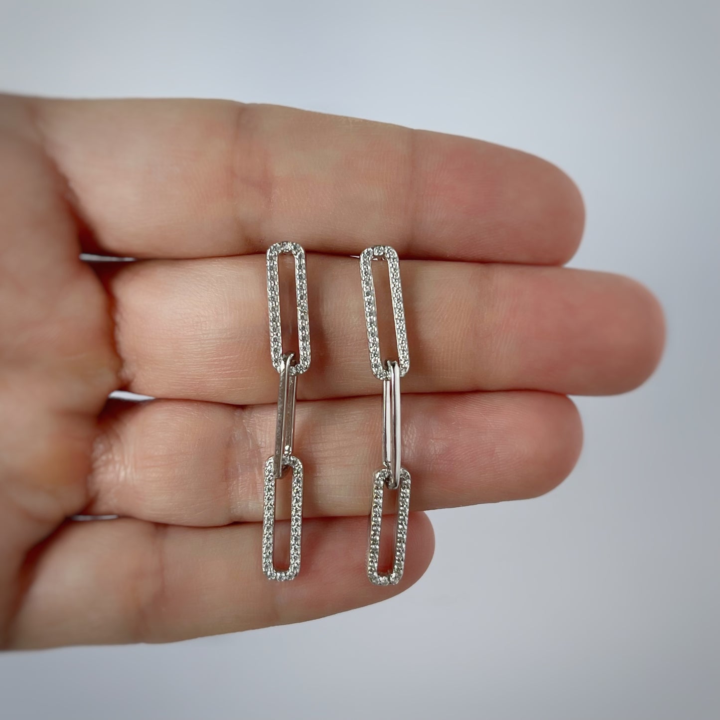 Arete largo paper clip de plata con baño platino y circonitas blancas