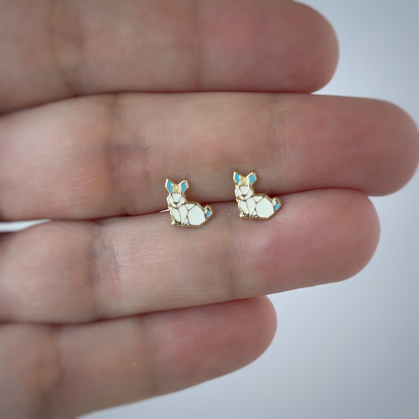 Aretes en oro amarillo 14K con conejo esmaltado blanco y orejas celestes con tope rosca