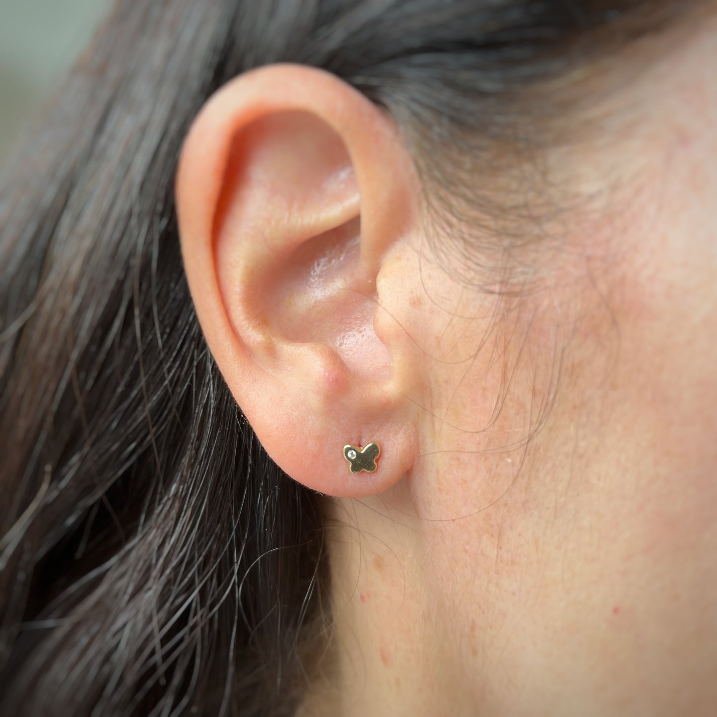 Aretes en oro amarillo 14k con mariposita y un circón con broche rosca