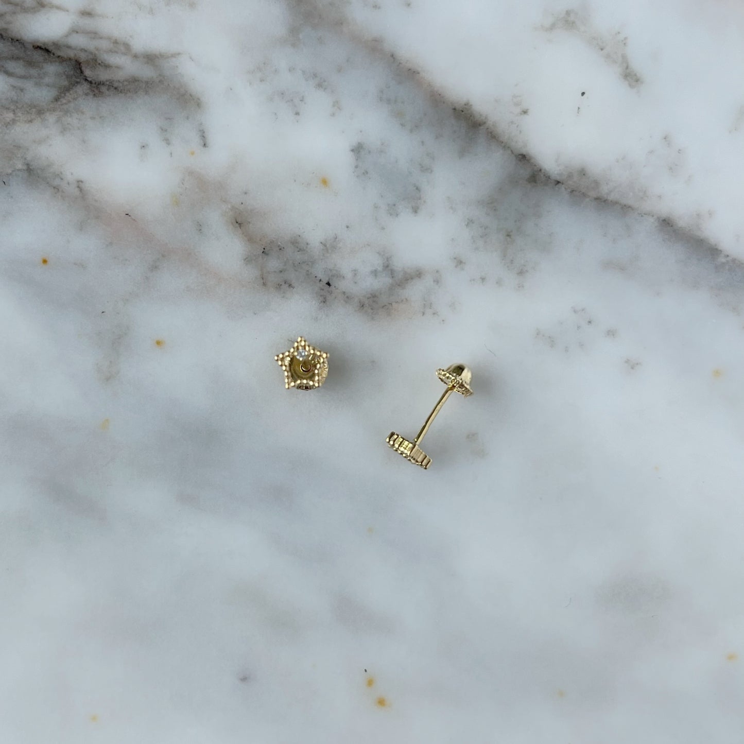 Aretes en oro amarillo 18k estrellita delineada con diamante con broche rosca