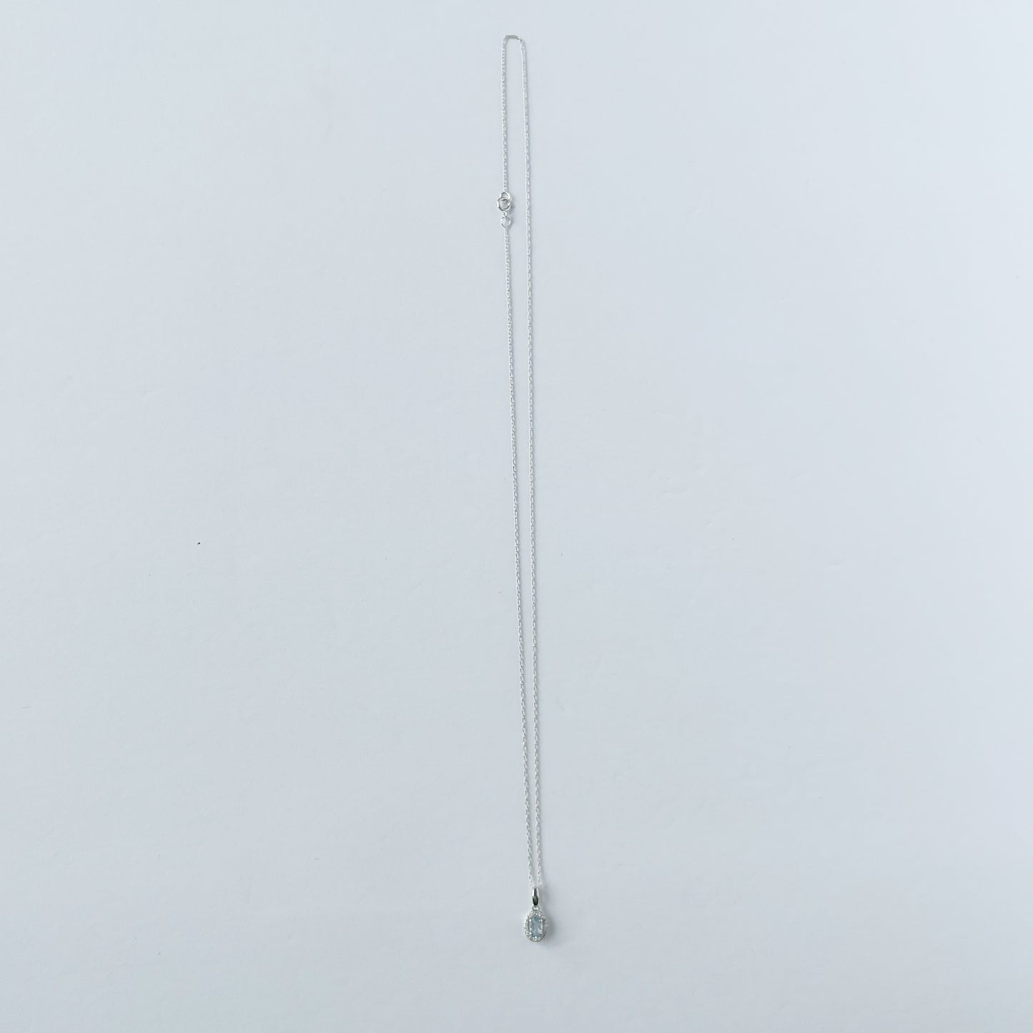 Collar en oro blanco 10k con dije de aquamarina ovalada y halo de diamantes.05ctw