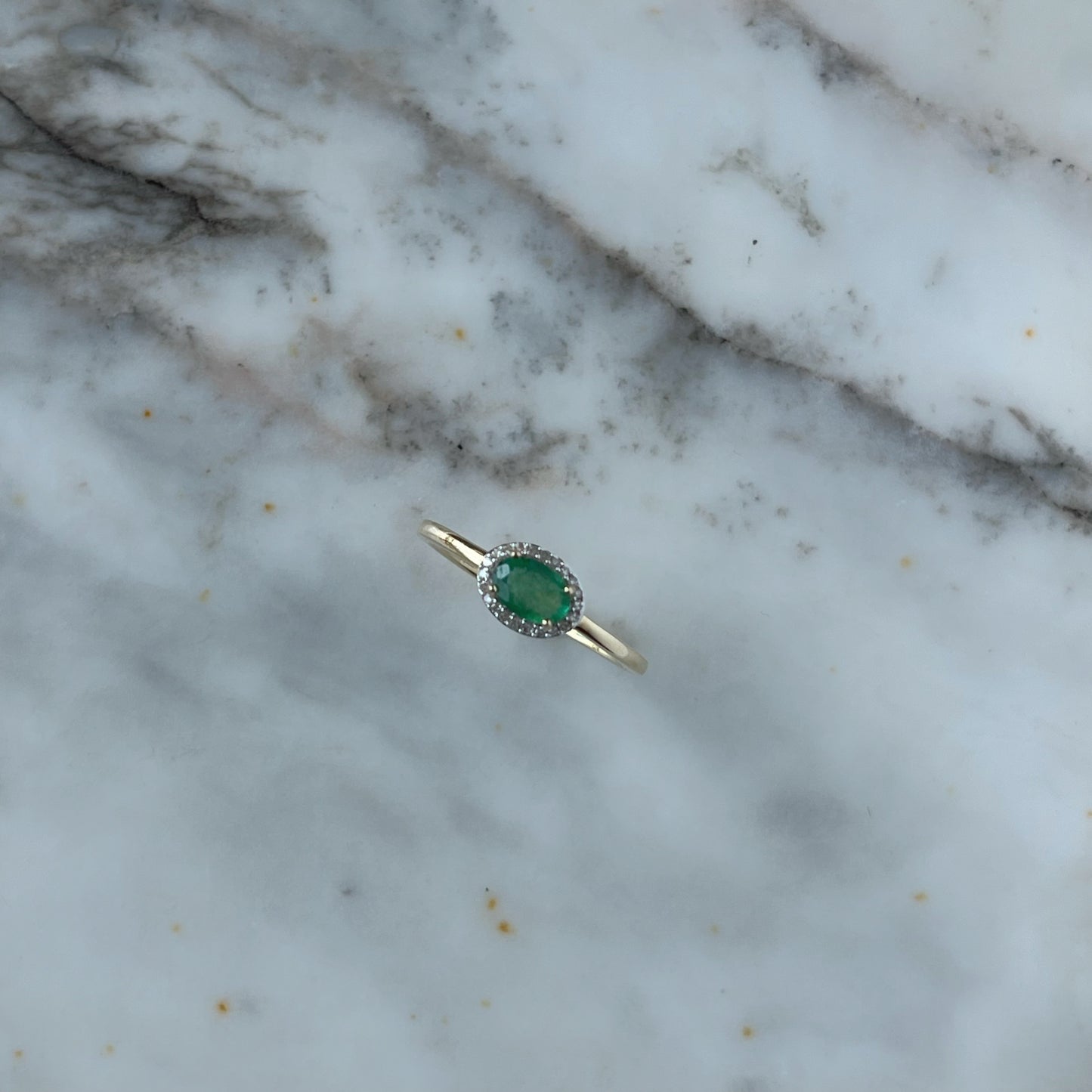 Anillo en oro amarillo 14k con esmeralda ovalada y halo de diamantes 0.10ctw