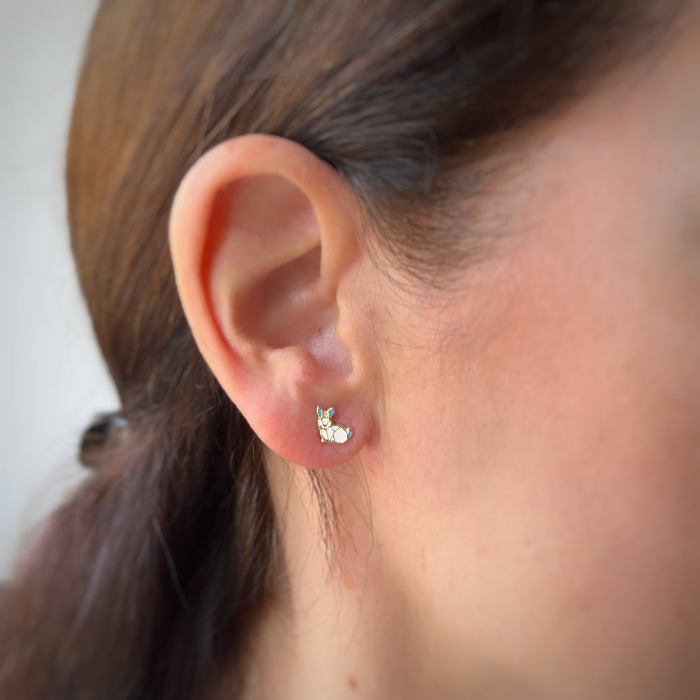Aretes en oro amarillo 14K con conejo esmaltado blanco y orejas celestes con tope rosca
