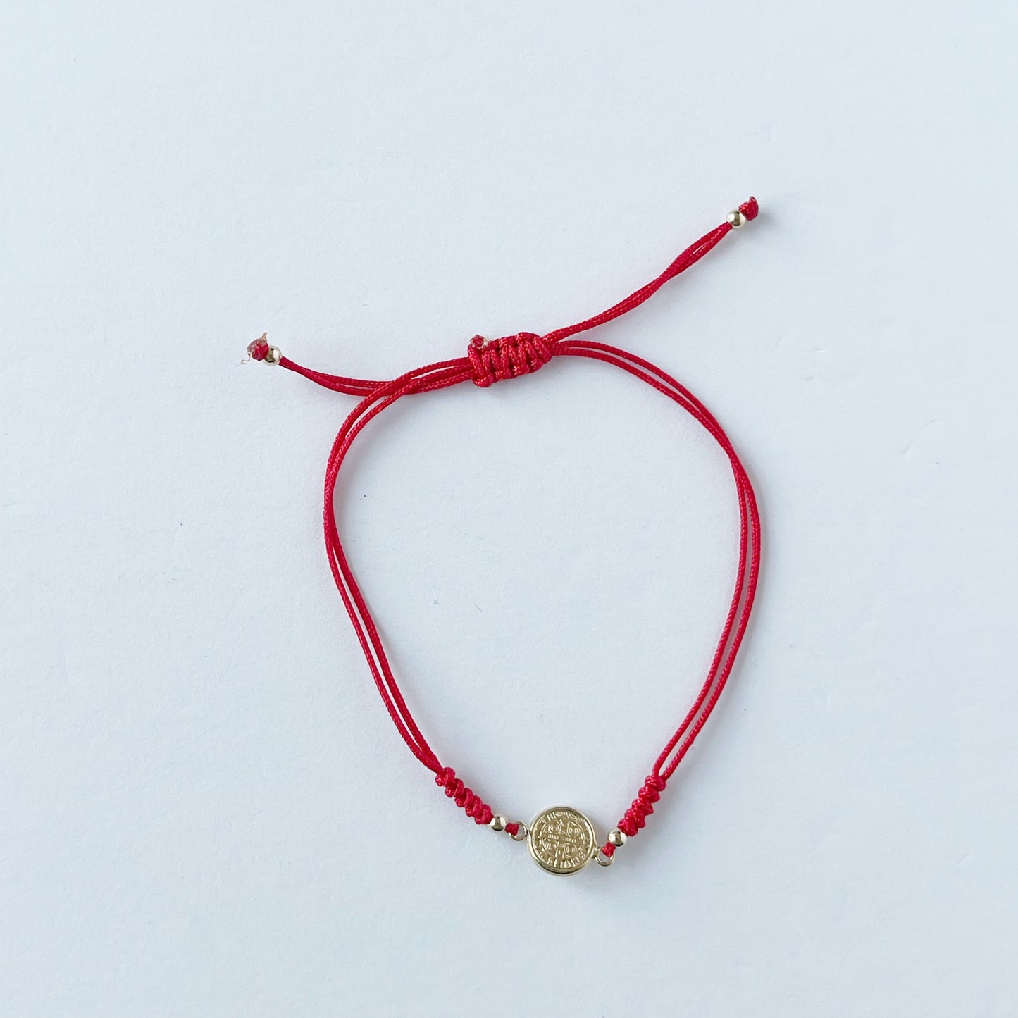 Pulsera de San benito en oro amarillo de 14K con cordón rojo
