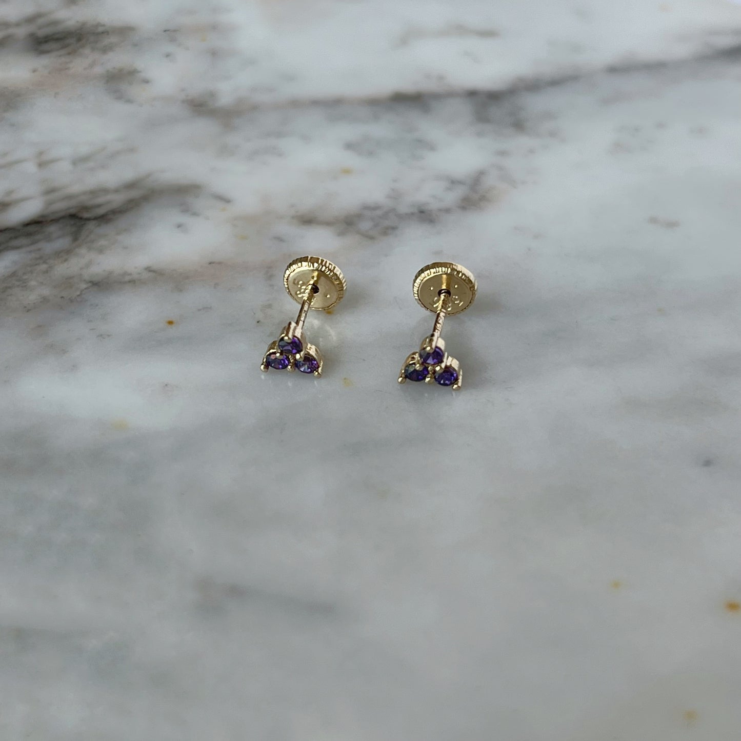 Aretes tres circonitas de color morado en oro amarillo de 14k con tope rosca