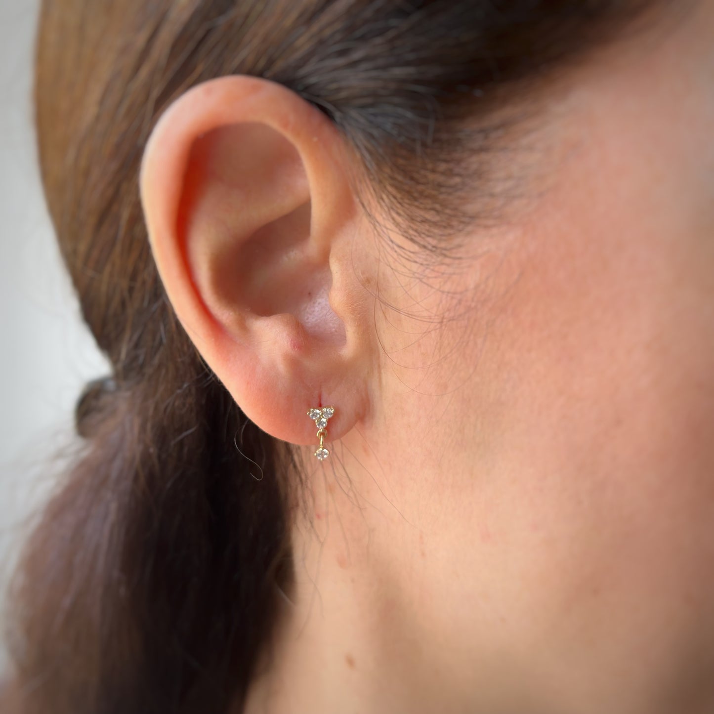 Arete single con tres circonitas blancas y una circonita colgante en oro amarillo de 14K con tope rosca