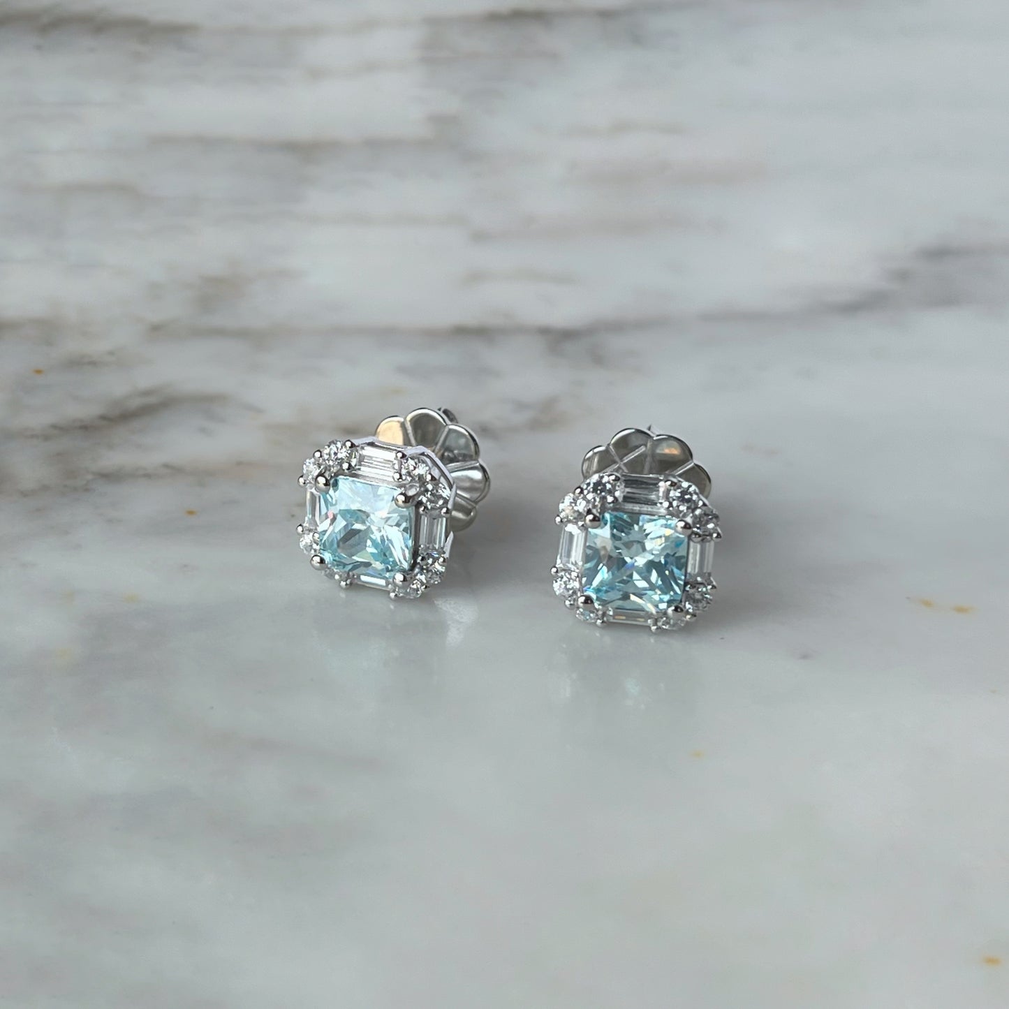 Arete de plata con baño platino cuadrado y circonita aquamarina con halo de circonitas blancas