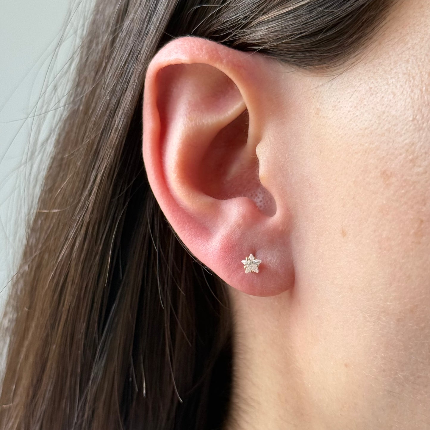 Aretes mini estrella con circón blanco en oro amarillo 14K con tope rosca