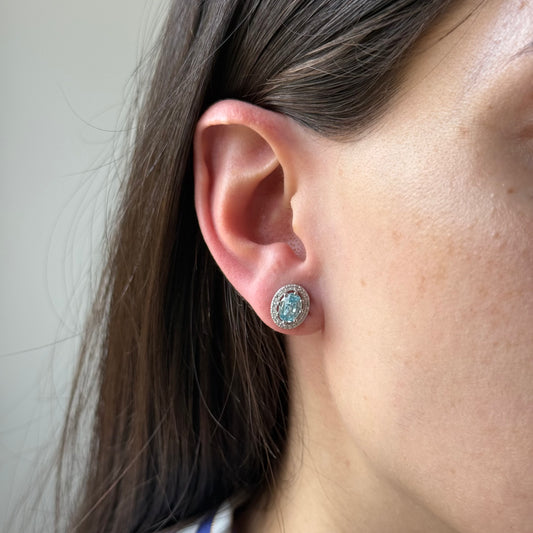 Aretes de plata con topacio azul ovalado y halo de circones
