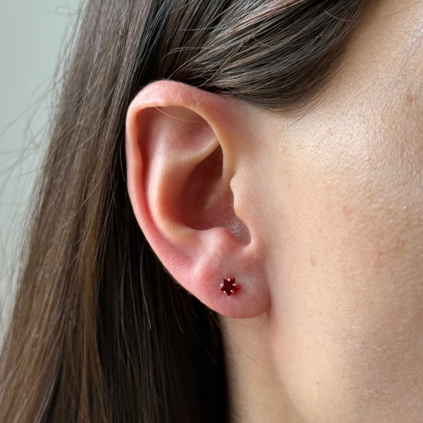 Aretes mini estrella con circón rojo en oro amarillo 14K con tope rosca