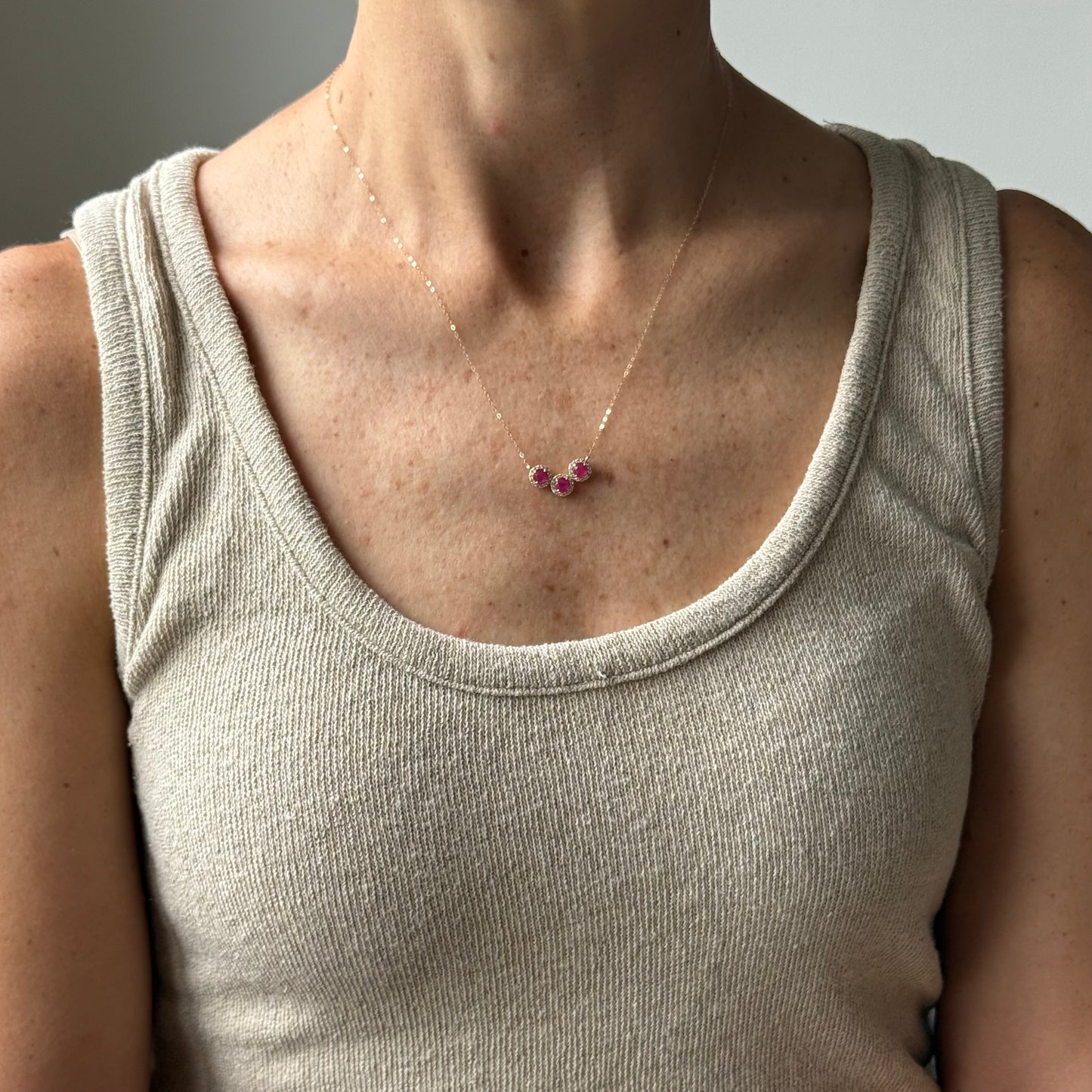 Collar en oro amarillo 14K con rubíes redondos y halo de diamantes 0.25ctw