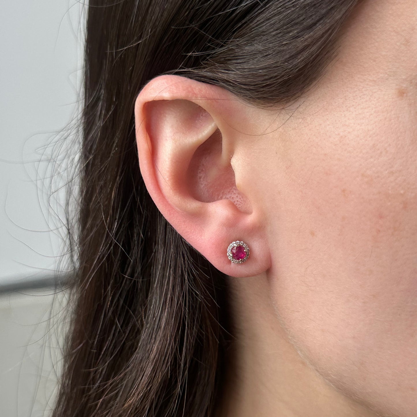Aretes redondos en oro blanco 10k con rubíes y halo de diamantes 0.10ctw