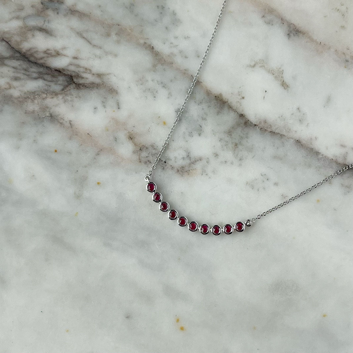 Collar en oro blanco 10k con curva de rubíes biselados