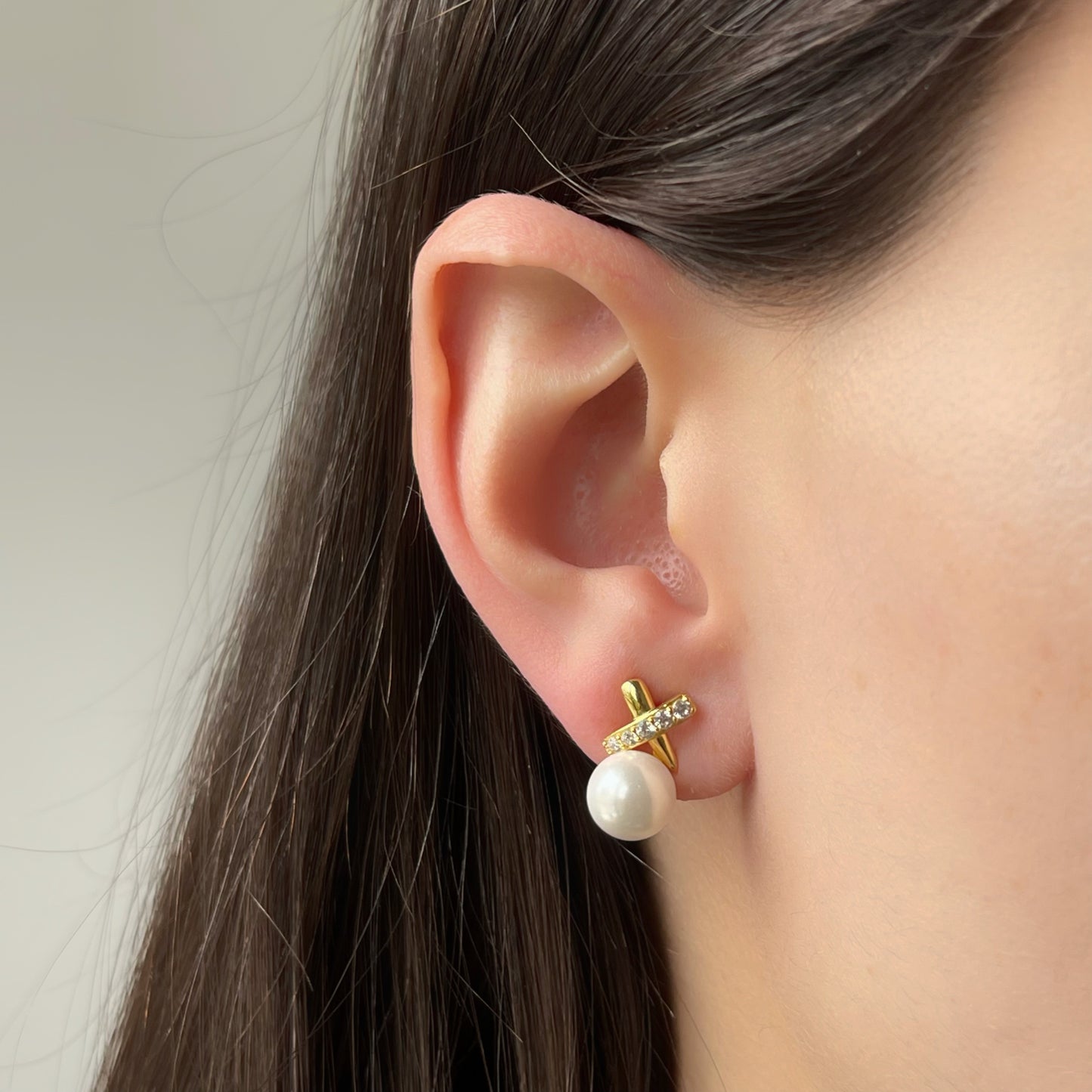 Aretes de plata con baño de oro amarillo con perla y una X arriba con línea de circonitas