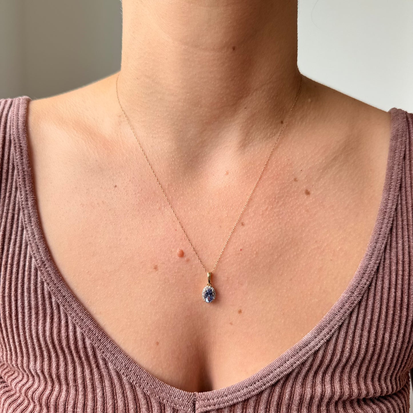 Collar en oro amarillo 10k con dije de tanzanita ovalada y halo de diamantes