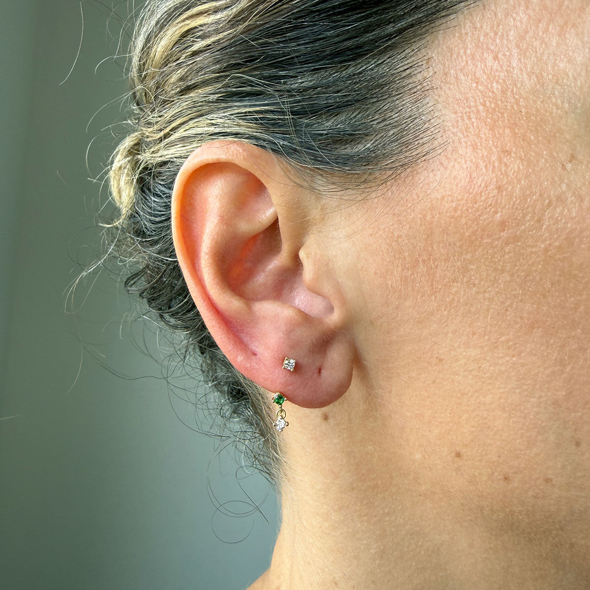 Arete piercing curva en oro amarillo 14k con circonitas blancas y verde