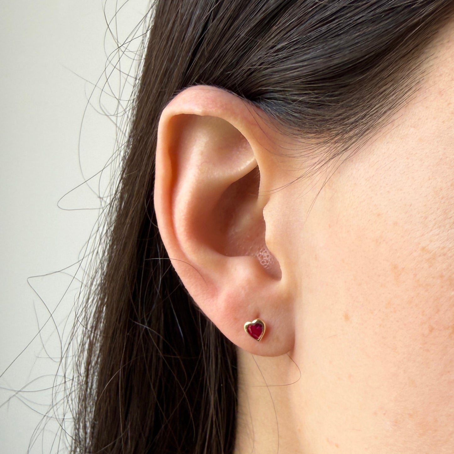 Aretes en oro amarillo 14k con corazón de circonita roja biselado con tope rosca