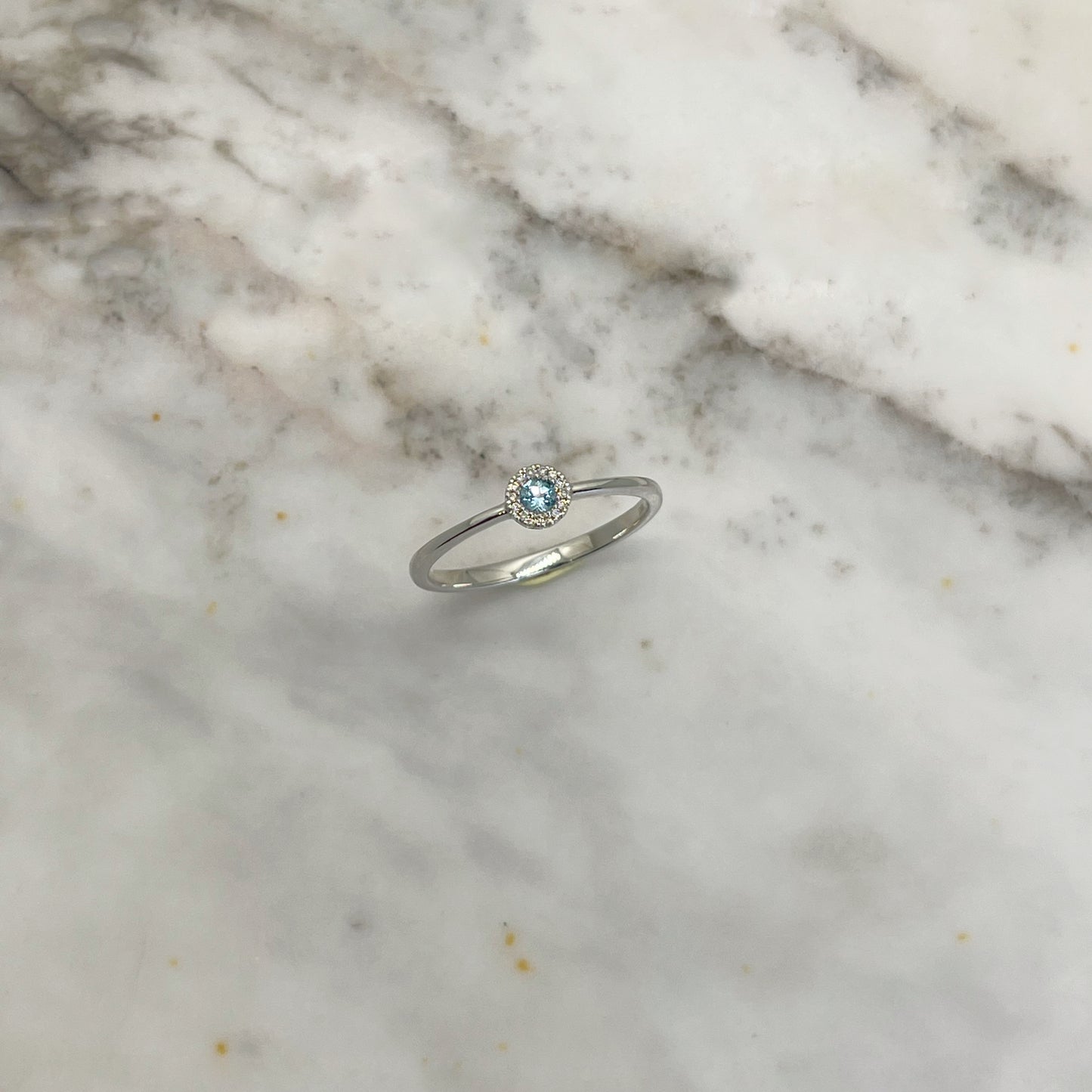 Anillo en oro blanco 10k con topacio azul y halo de diamantes 0.04ctw