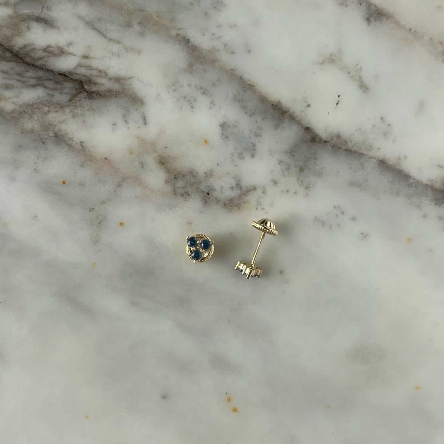Aretes tres circonitas color celeste de 3mm en forma de triángulo en oro amarillo de 14k con tope ortopédico