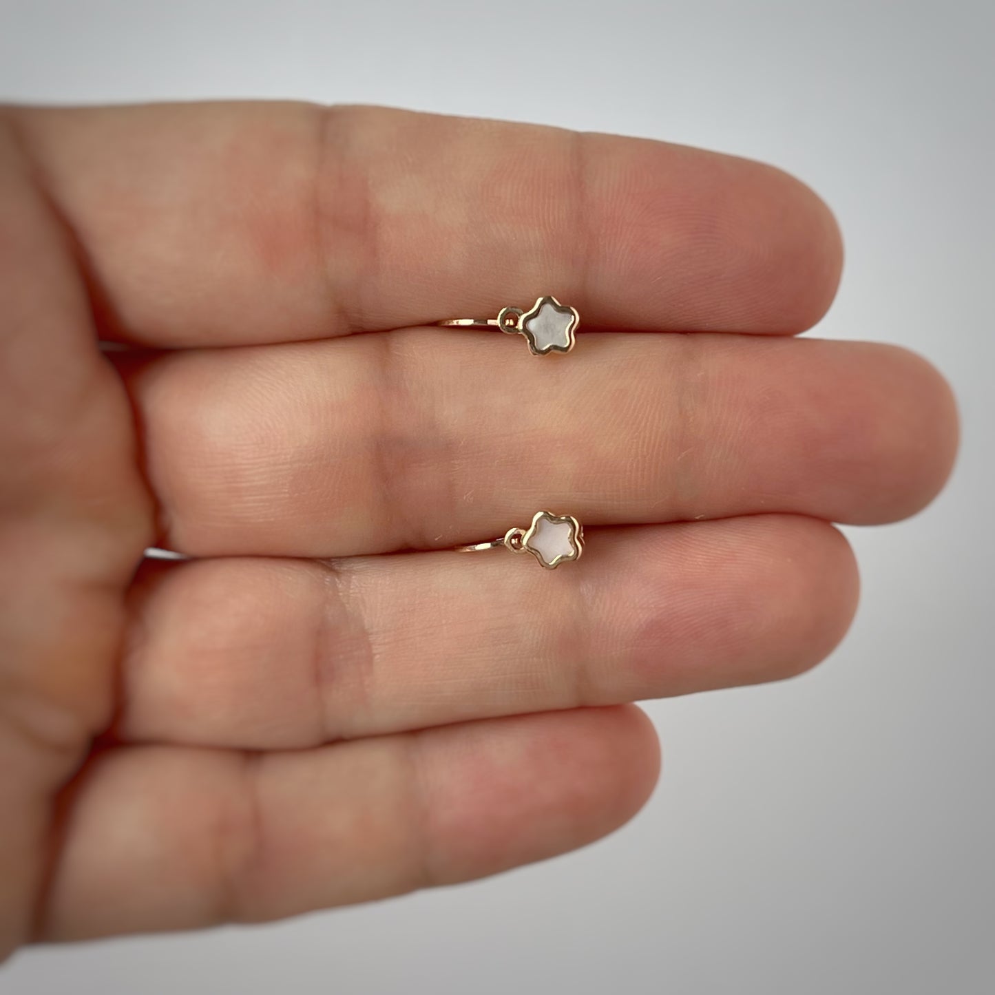 Arete gancho frances con florcita en madre perla en oro rosado de 14k