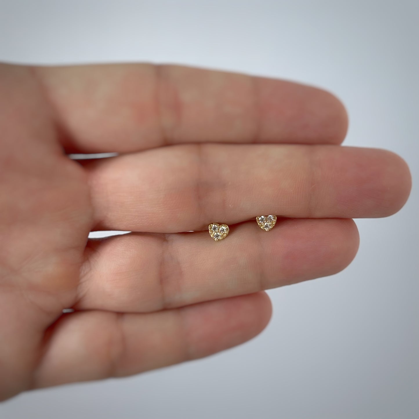 Aretes en forma de corazón con tres circonitas blancas en oro de 14k con tope ortopédico
