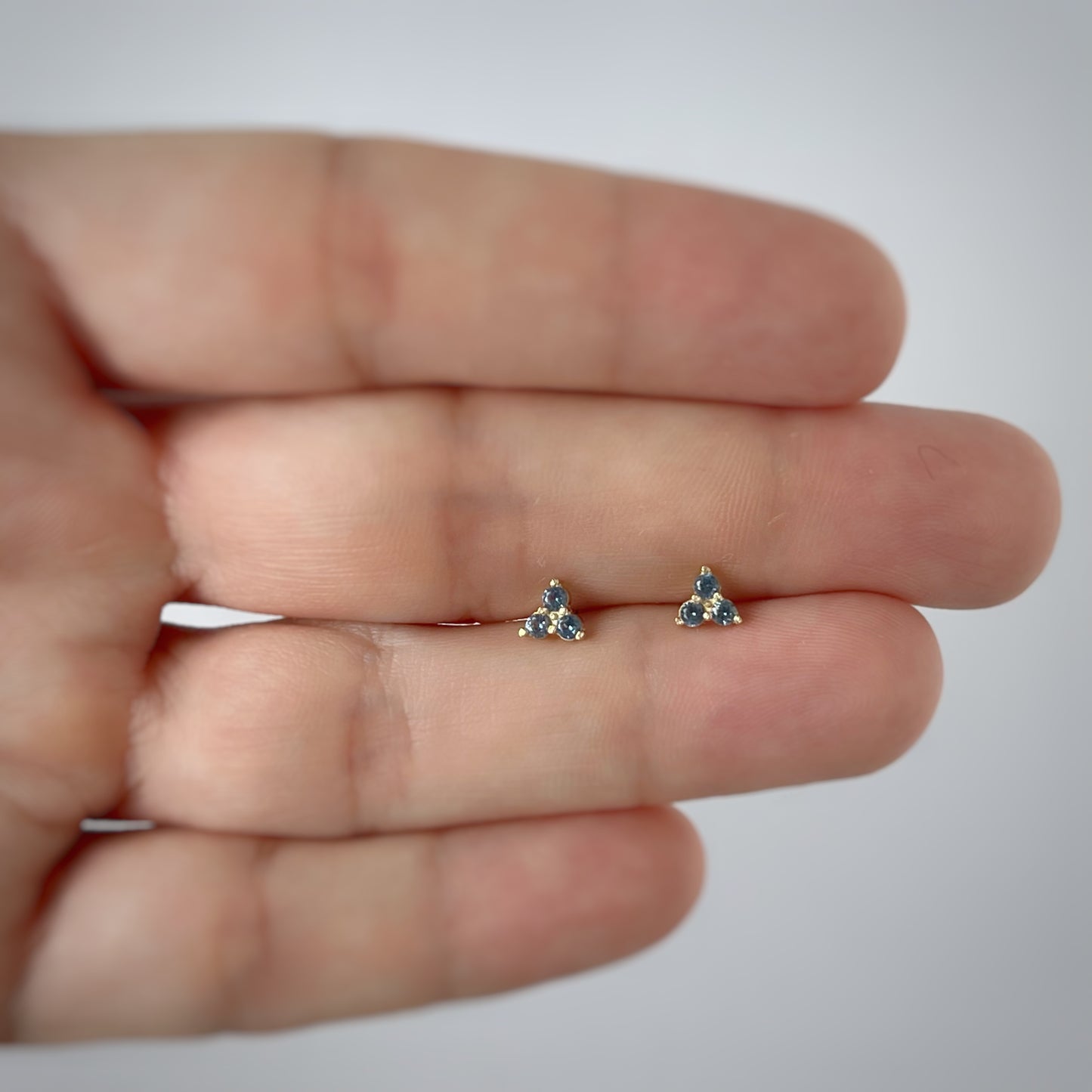 Aretes tres circonitas color celeste de 3mm en forma de triángulo en oro amarillo de 14k con tope ortopédico