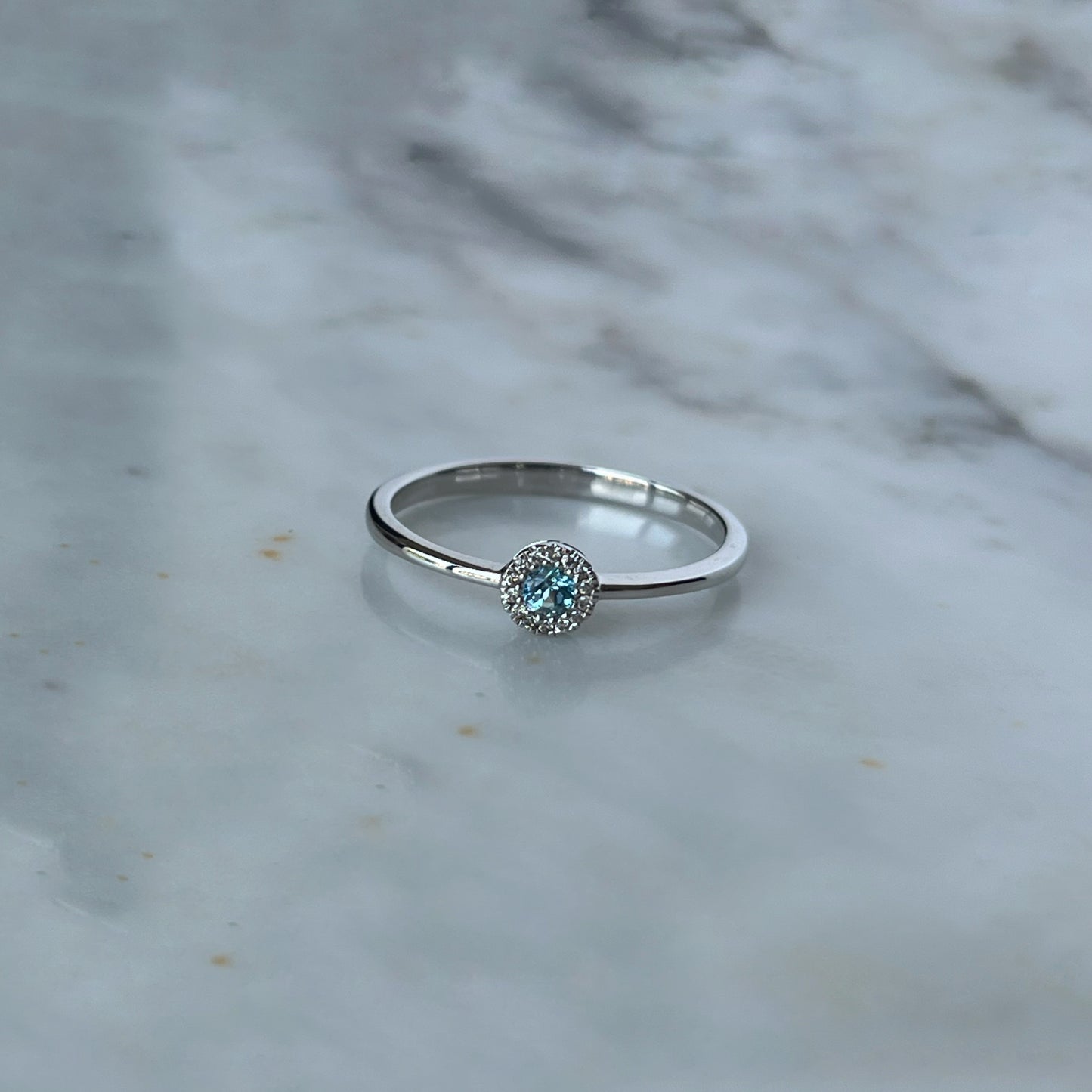 Anillo en oro blanco 10k con topacio azul y halo de diamantes 0.04ctw