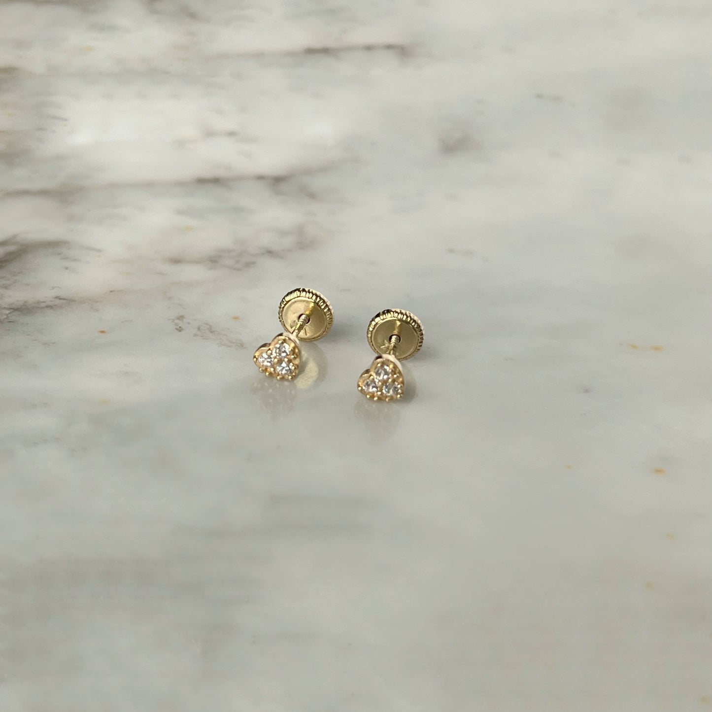 Aretes en forma de corazón con tres circonitas blancas en oro de 14k con tope ortopédico
