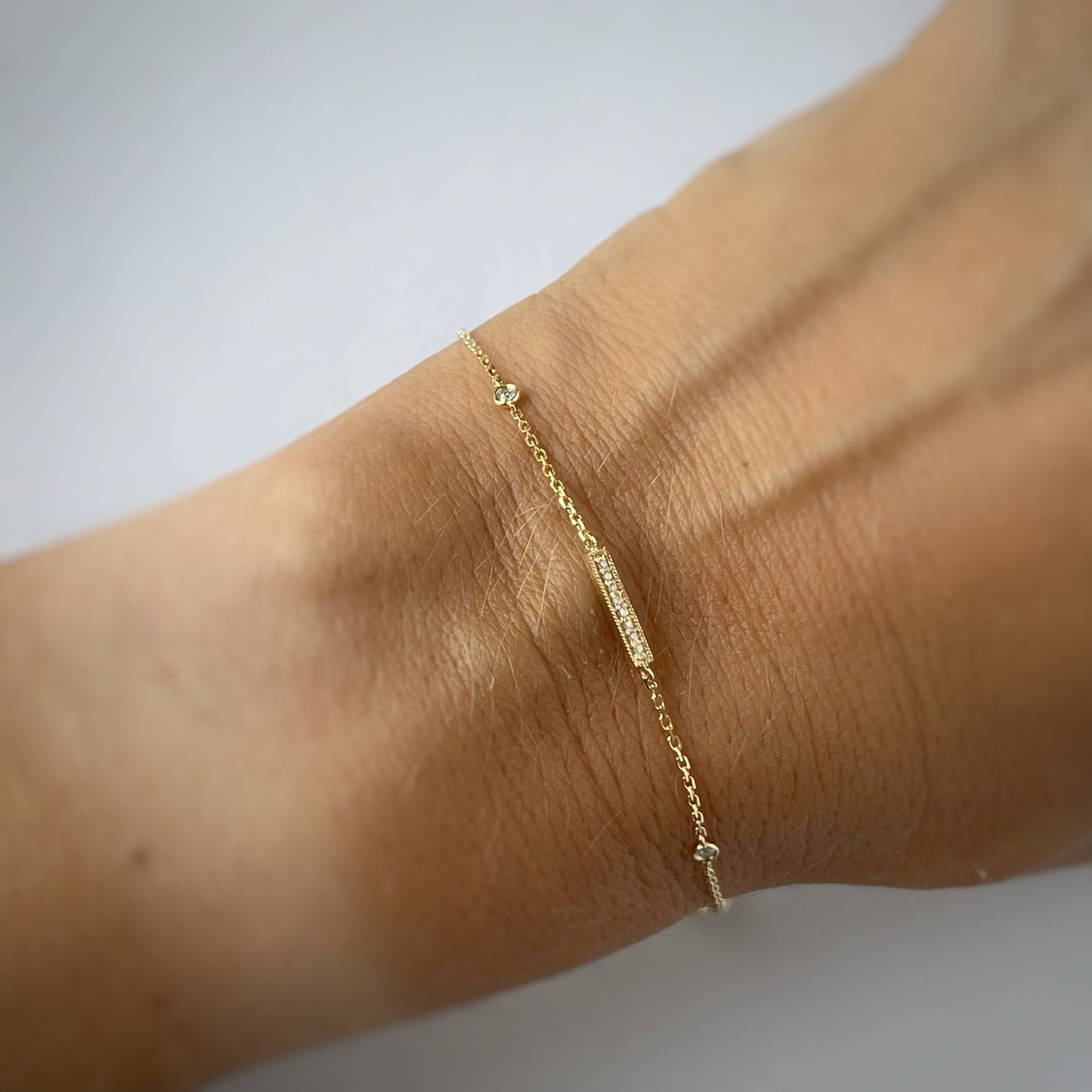 Pulsera en oro amarillo 14k con barrita de diamantes y dos diamantes biselados 0.05