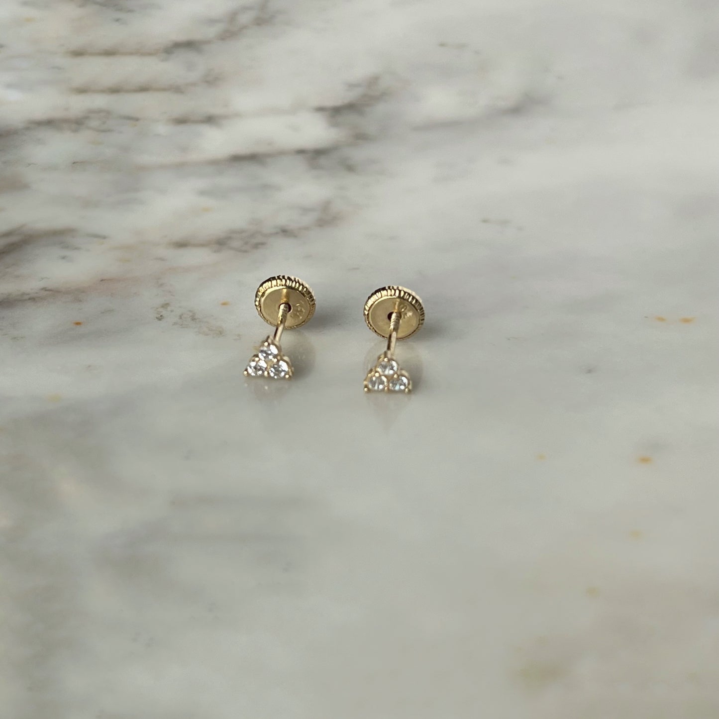 Aretes tres circonitas blancas mini en oro de 14k con tope ortopédico