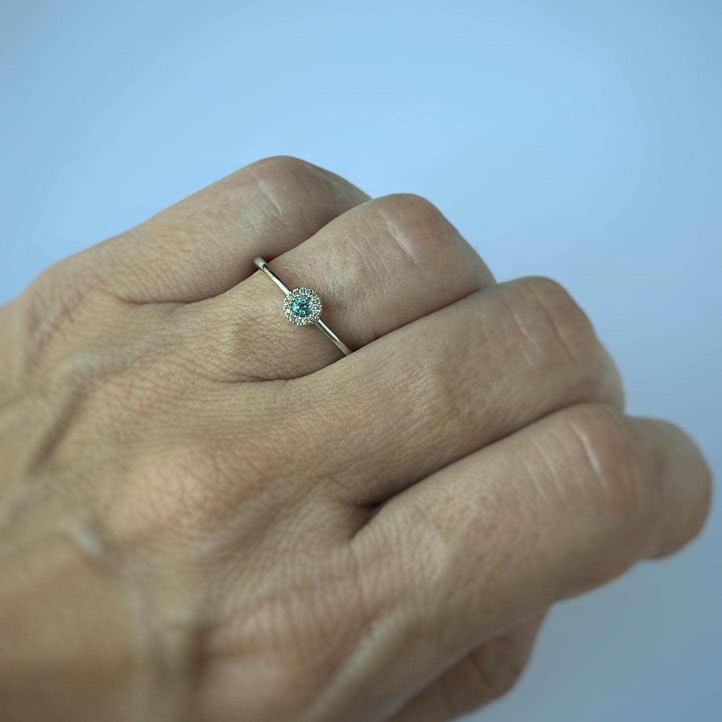 Anillo en oro blanco 10k con topacio azul y halo de diamantes 0.04ctw