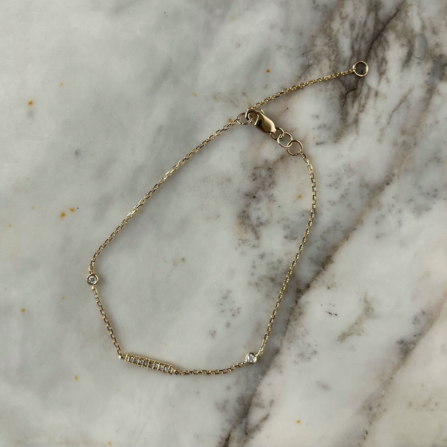 Pulsera en oro amarillo 14k con barrita de diamantes y dos diamantes biselados 0.05