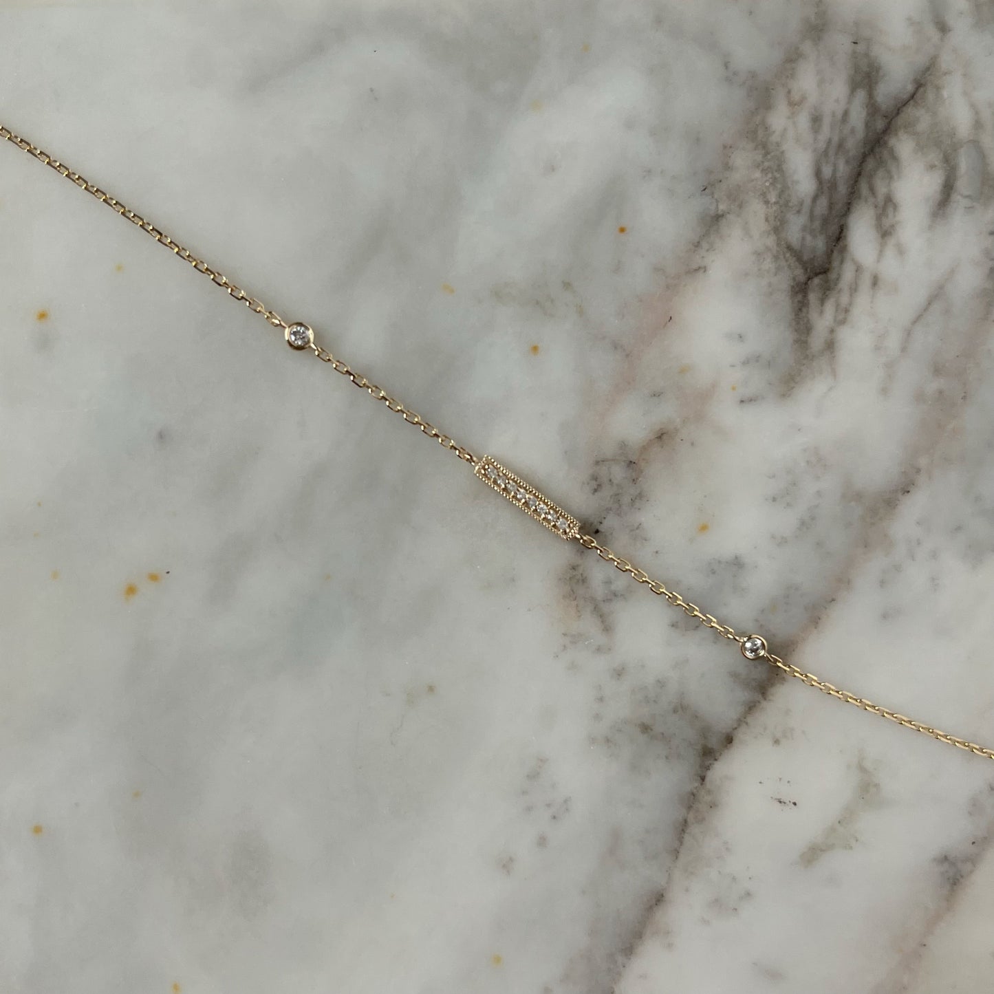 Pulsera en oro amarillo 14k con barrita de diamantes y dos diamantes biselados 0.05