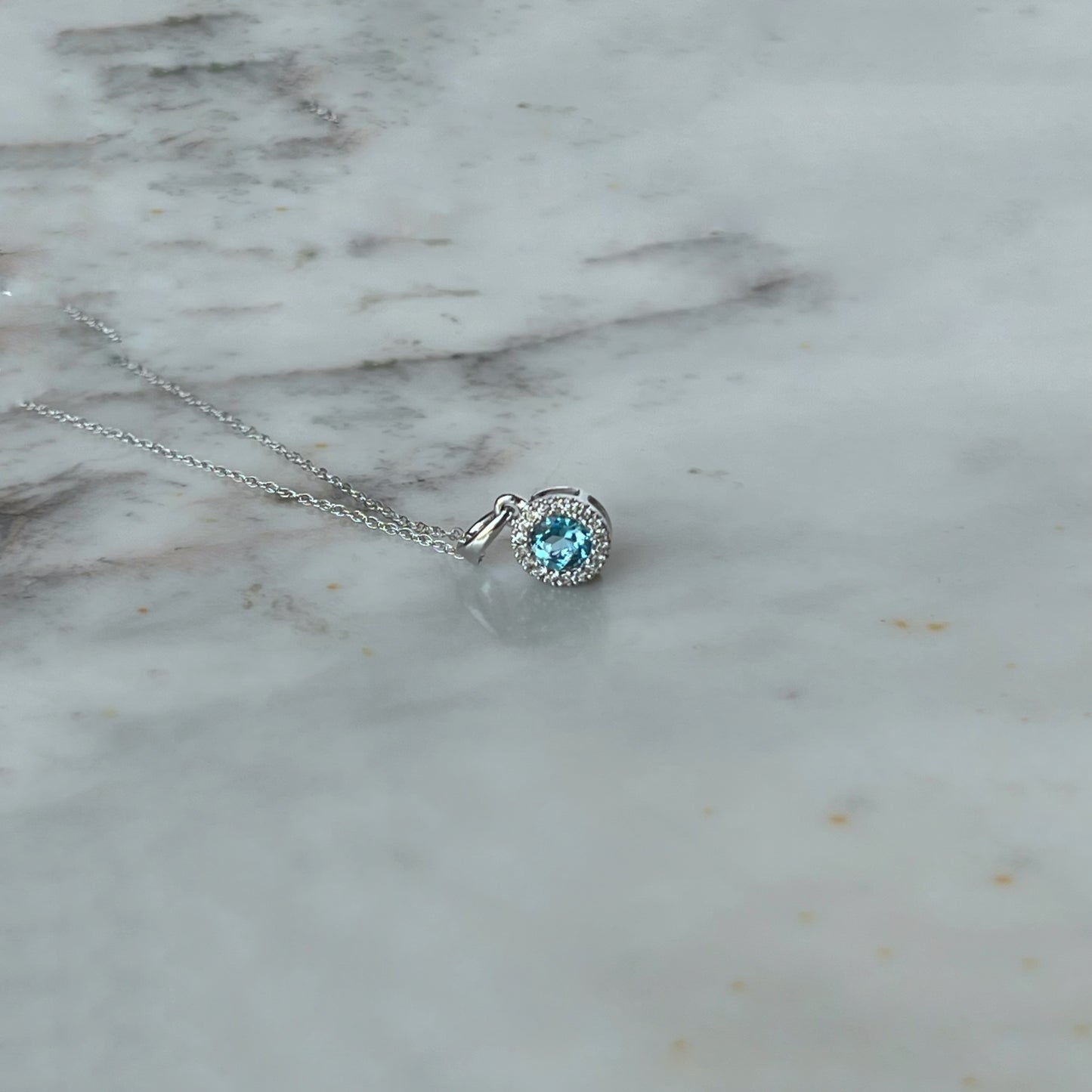 Collar en oro blanco 10k con dije de topacio azul y halo de diamantes 0.06ctw