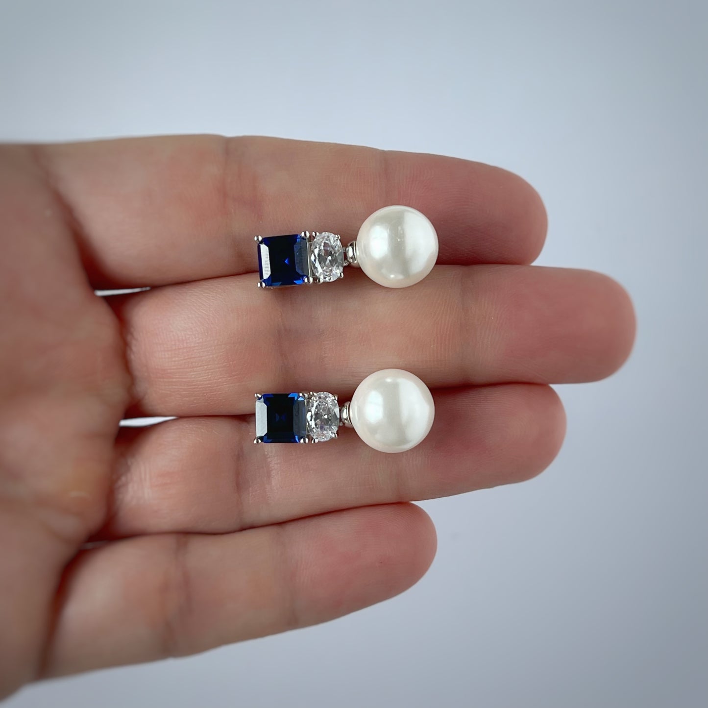 Aretes en plata con baño de platino con circonita azul y perla de cristal