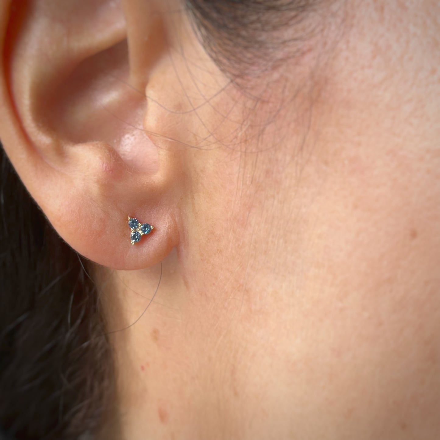 Aretes tres circonitas color celeste de 3mm en forma de triángulo en oro amarillo de 14k con tope ortopédico