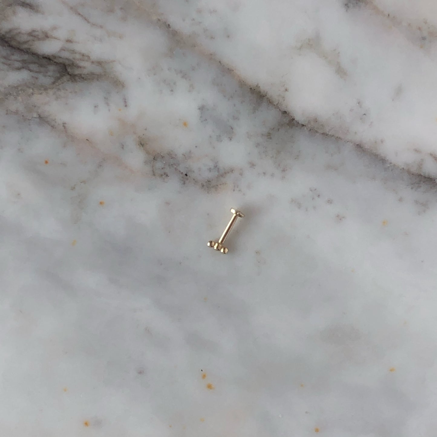 Aretes single en oro amarillo 14k de 3 bolitas y rosca interna para piercing