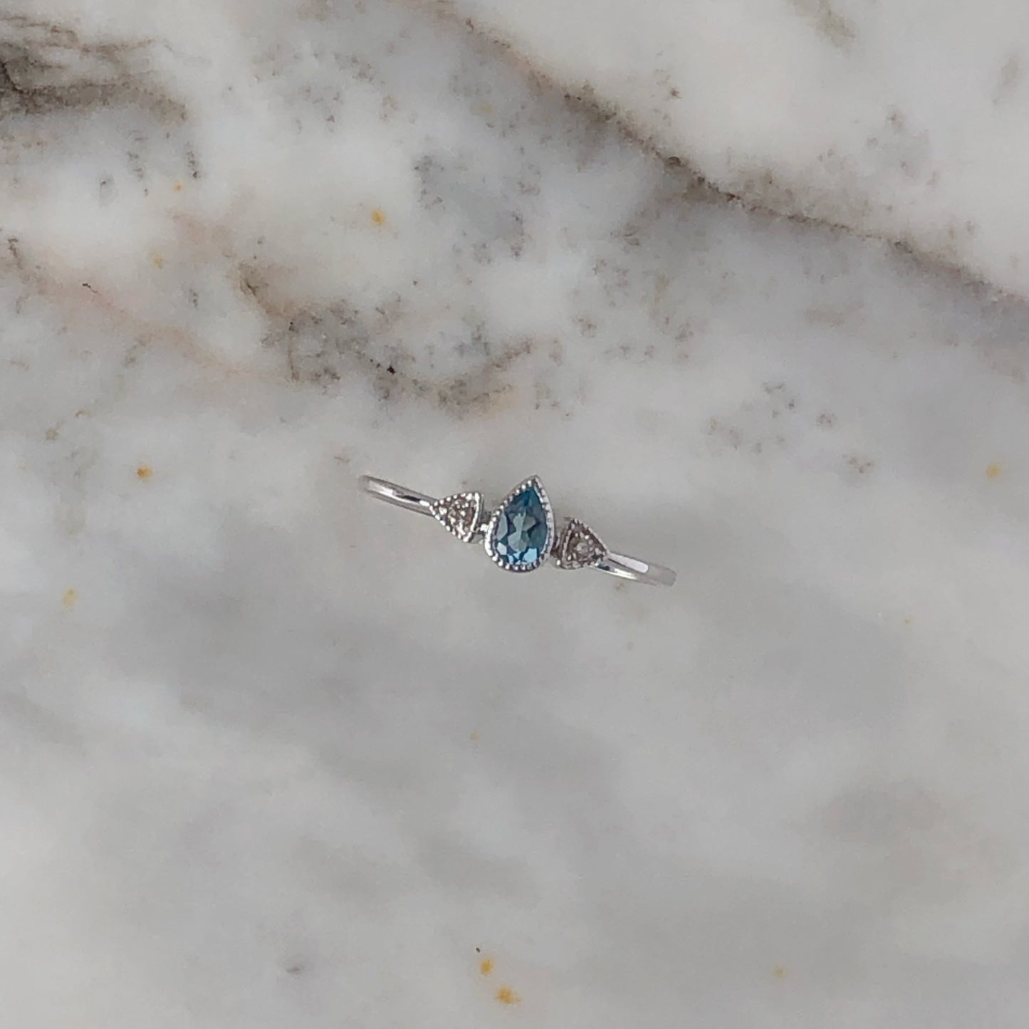 Anillo con Topacio azul en corte pera y diamantes en oro blanco 10k