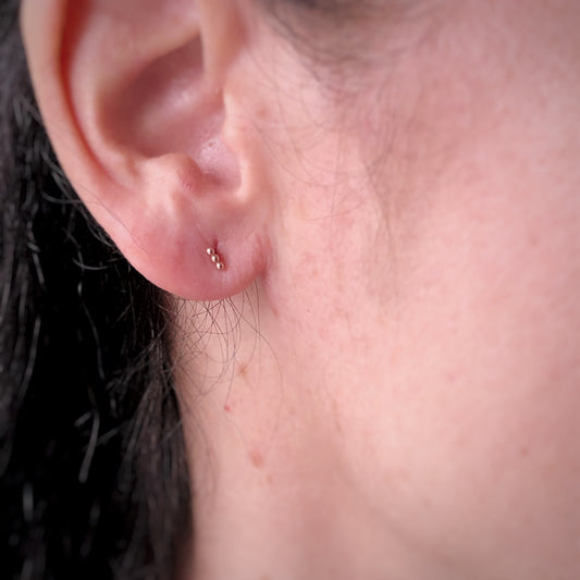 Aretes single en oro rosa 14k de 3 bolitas y rosca interna para piercing