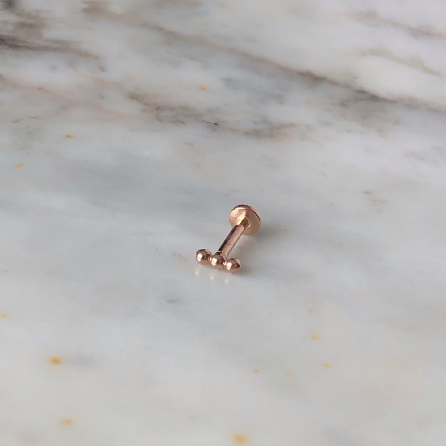 Aretes single en oro rosa 14k de 3 bolitas y rosca interna para piercing