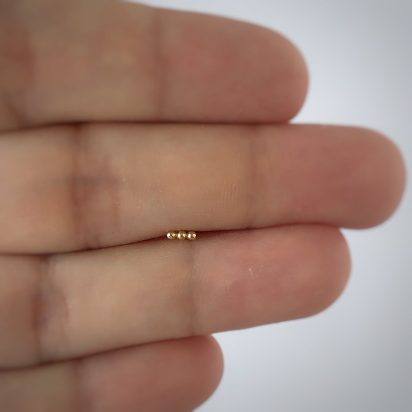 Aretes single en oro amarillo 14k de 3 bolitas y rosca interna para piercing